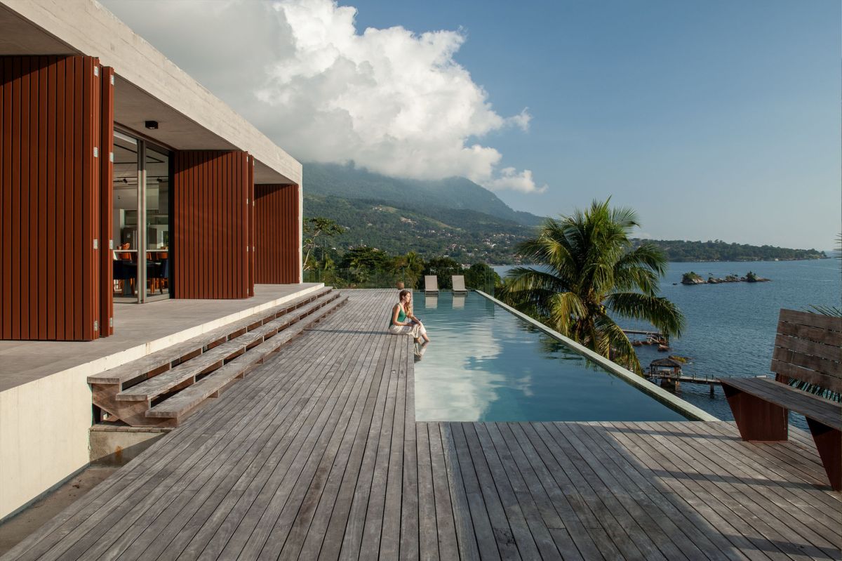the main volumes opens up towards a wooden deck with an infinity pool