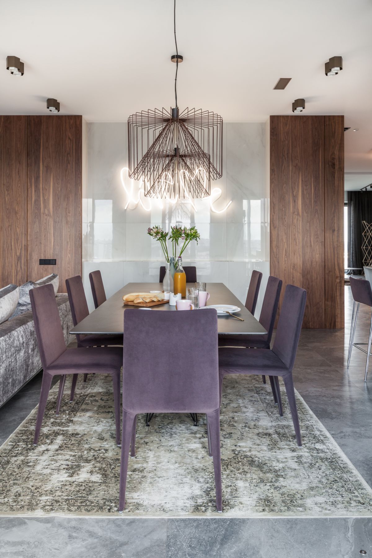 The dining area is framed by a soft and velvety area rug and features beautiful purple chairs