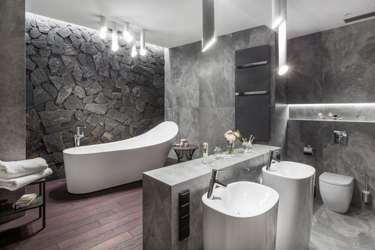 The master bathroom is designed with tones of gray and dark-stained wood for a spa-like vibe
