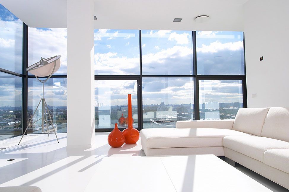 The all-white walls, sofa and flooring combined with the large windows give this living room a very pure and airy look