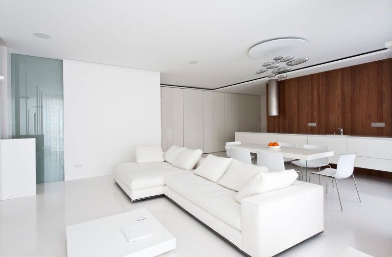 The white living room furniture is complemented here by wood paneling on the accent wall